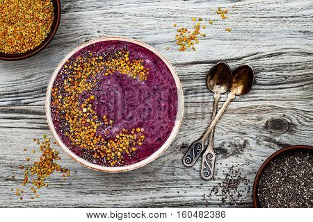 Acai breakfast superfoods smoothies bowl with chia seeds bee pollen toppings. Immune boosting anti inflammatory smoothie with turmeric honey and maca powder. Overhead top view flat lay copy space