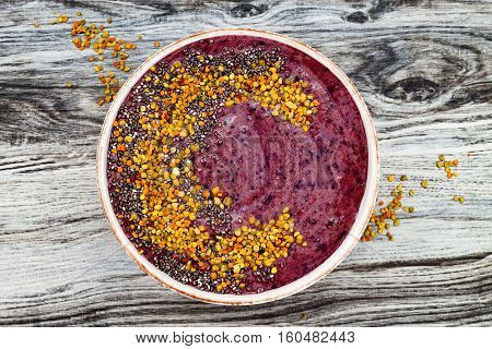 Acai breakfast superfoods smoothies bowl with chia seeds bee pollen toppings. Immune boosting anti inflammatory smoothie with turmeric honey and maca powder. Overhead top view flat lay copy space