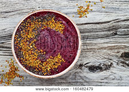 Acai breakfast superfoods smoothies bowl with chia seeds bee pollen toppings. Immune boosting anti inflammatory smoothie with turmeric honey and maca powder. Overhead top view flat lay copy space