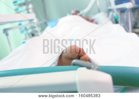 Unconscious patient in hospital bed. Foot view