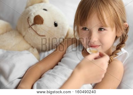 Small sick girl taking medicine