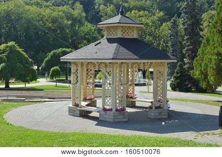Elegant gazebo surrounded with lush park trees in summertime