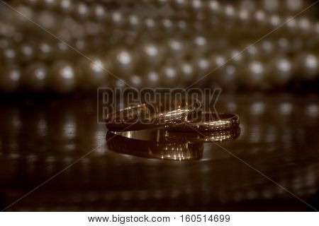 Wedding rings on the table with reflection and necklace on background