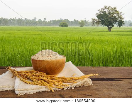 Jasmine rice in bowl and gloden spike on wooden table of morning framland backgroundwith copy space