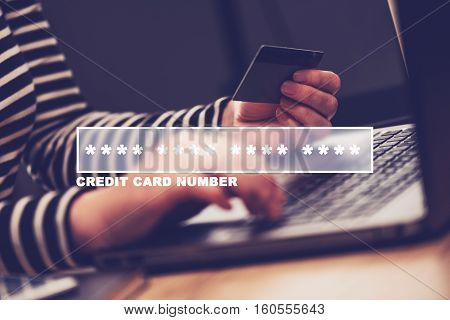 Woman typing credit card number for online shopping - close up of female hands using e-wallet credentials for an internet purchase transaction
