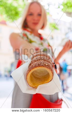 Young female tourist with traditional czech dessert called trdelnik in Prague. Czech Republic. Outdoor
