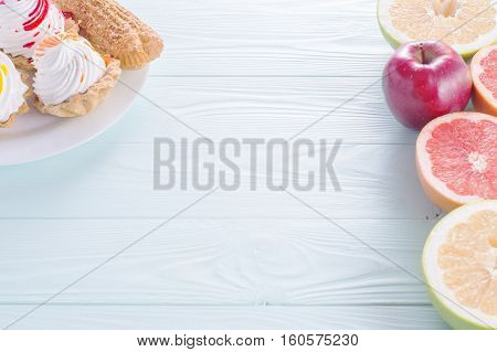 Choosing between Fruits and Sweets. Healthy versus unhealthy food. Weight Loss. Unhealthy tempting cakes and healthy fruits.