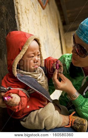 HA GIANG, VIETNAM: MAR 15, 2010: Portrait of an unidentified Hmong child crying on the arms of a tourist in Dong Van rocky prairie.