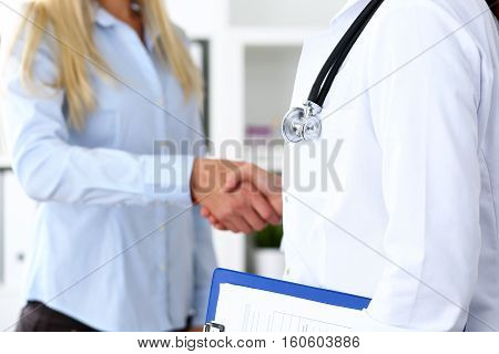 Female medicine doctor shake hand as hello with businesswoman in office closeup. Welcoming friend introduction or thanks gesture. Tests advertisement concept. Therapeutist ready to examine patient