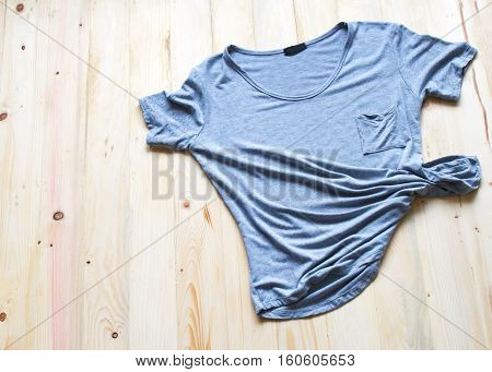 fashionable women's clothes on a wood background in summer T-shirt gray vertical zigzag pattern crumpled on the floor a wooden top view.