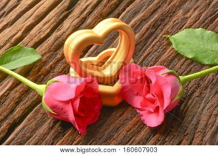 The wood hearts and two pink rose on bark.