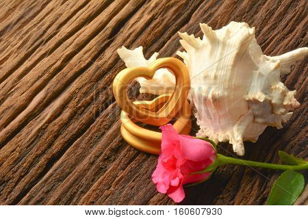 The wood hearts ,sea shell and two pink rose on bark.