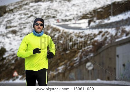 young healthy sport man running on road at snow mountains in trail runner hard workout in energy and endurance concept with a beautiful cold winter background