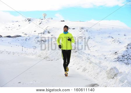 young healthy sport man running in snow mountains in trail runner hard workout in energy and endurance concept with a beautiful cold winter background