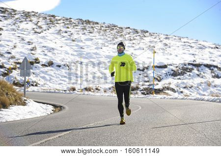 young healthy sport man running on road at snow mountains in trail runner hard workout in energy and endurance concept with a beautiful cold winter background