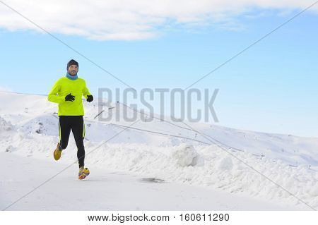 young healthy sport man running in snow mountains in trail runner hard workout in energy and endurance concept with a beautiful cold winter background