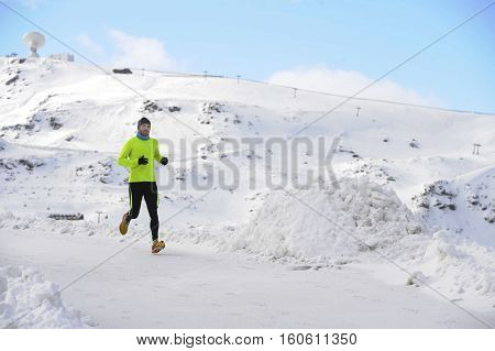 young healthy sport man running in snow mountains in trail runner hard workout in energy and endurance concept with a beautiful cold winter background