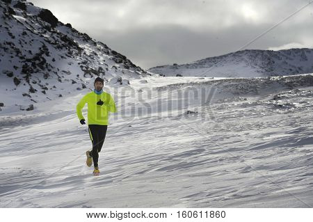 young healthy sport man running in snow mountains in trail runner hard workout in energy and endurance concept with a beautiful cold winter background