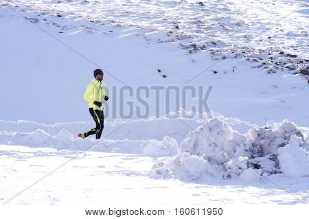 young healthy sport man running in snow mountains in trail runner hard workout in energy and endurance concept with a beautiful cold winter background