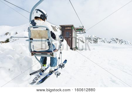Back view of skier riding a lift. Skking in the mountains.