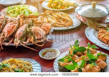 Thai style set of seafood insist of Thai steamed curry fish in banana leaf cups decorated with basil leaf (Hor Mok Pla) steamed crab/prawn/shrimp with seafood sauce
