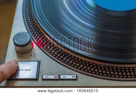 A fan of high-fidelity music starts the record player for listening to a vinyl record