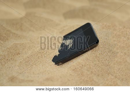 Mobile phone in sand. Isolated abstract macro photo