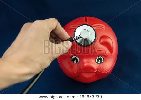 Piggy Bank and Stethoscope with Selective Focus on a blue Background.