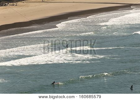 Surfer riding a wave towards shore. Sunny summer day on the Pacific Ocean (Newport, Oregon, USA).