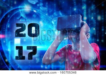 Boy with virtual reality simulator against digitally generated black and blue matrix
