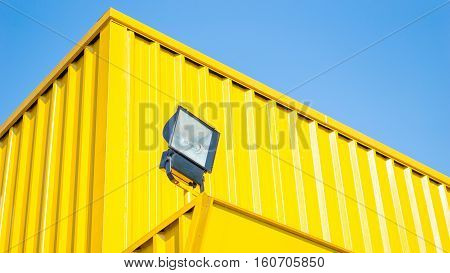 Spotligth lamp and building concept - Outdoor spotlight lamp with yellow container wall and copy space