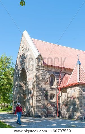 Yantarny, Russia - June 22, 2010: Woman walking near temple in honor of the Kazan Icon of the Mother of God in summer day