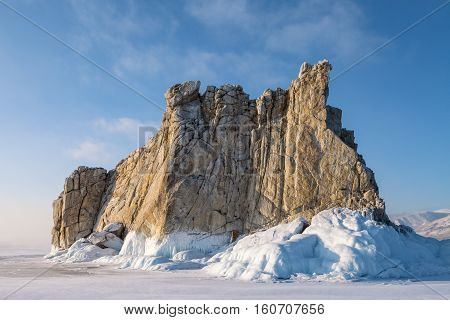Figured rock surrounded by ice on blue sky background