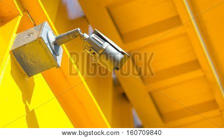 Security camera equipment concept - Black color CCTV camera surveillance on wall of yellow home or tower Safety system area control and copy space