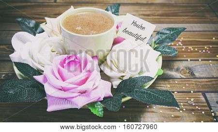 Rose Flowers On A Plate On A Wooden Table, A Note On The Paper