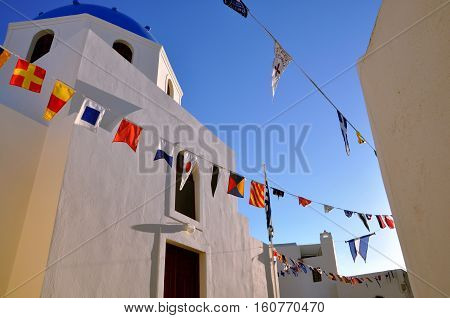 White orthodox church cathedral with blue dome and garland of flags of different countries on blue sky. concept of religion, union, peace,collaboration, globalization, pacifism, trip around the world