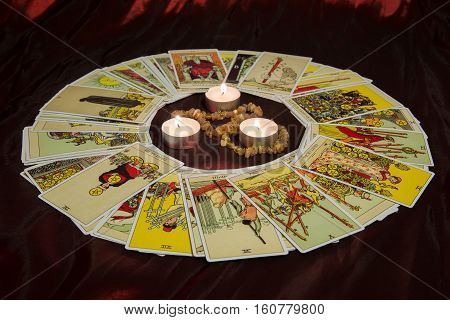 Moscow, Russia - December 4, 2016: Rider-Waite tarot cards and burning candle in center. Esoteric background.
