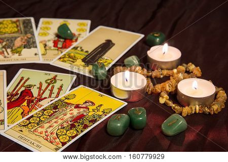 Moscow, Russia - December 4, 2016: Rider-Waite tarot cards with runes and burning candle. Esoteric background.
