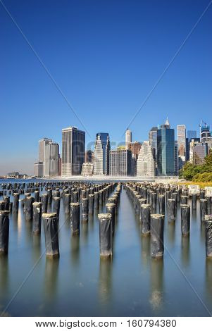 Old pier pylons and Downtown Manhattan New York City.