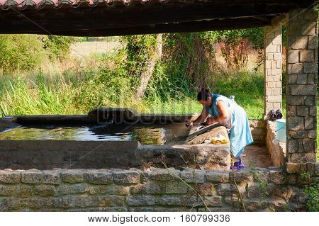 MELIDE SPAIN - AUGUST 14: A woman washes her clothes in the wash house on August 14 2016