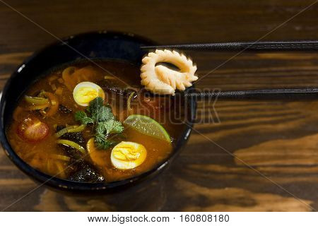 Traditional ramen soup with squid on a wooden table