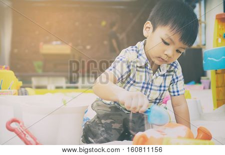 Japanese boy is playing in educational sandbox.