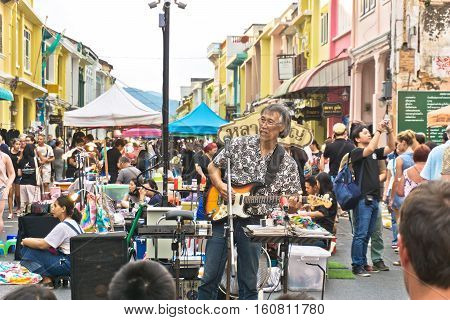PHUKET THAILAND SEPTEMBER 27: Street artist musician entertains tourists at the walking street among old building Chino Portuguese style on street of Phuket town Thailand on September 27 2016.