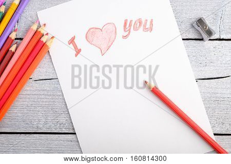 group different colored pencils on white paper on old wooden background closeup postcard for Valentine's day copy space for text top view
