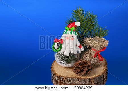 New Year composition Santa Claus with gifts on a wooden stump blue background