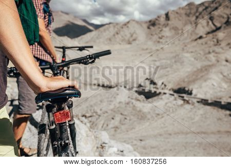 Close up image man hand on bicycle saddle. Two maountain bikers in Himalaya