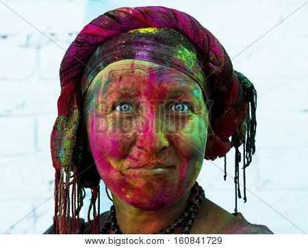 woman with blue eyes in vibrant colors on her face at Holi celebration in Rishikesh India