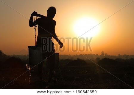 Old man transporting water in the field