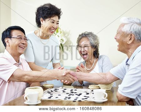 senior asian men shaking hands at the end of a weiqi game.