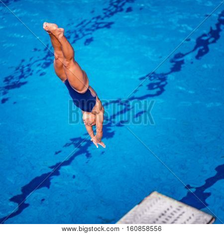 Female diver jumping into the pool from diving board